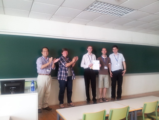 Photograph of organising committee members (Takayuki Ito and Catholijn Jonker) presenting the winners of the Most Social Agent award (Colin R. Williams, Enrico H. Gerding and Valentin Robu) with their prize.